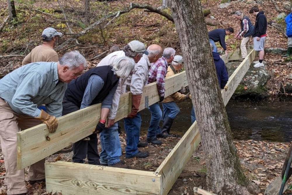 Group of people building a wooden structure on a trail in the woods