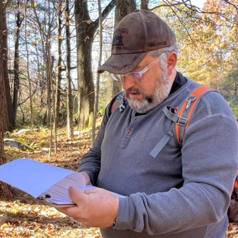 Man looking at papers while out in the woods