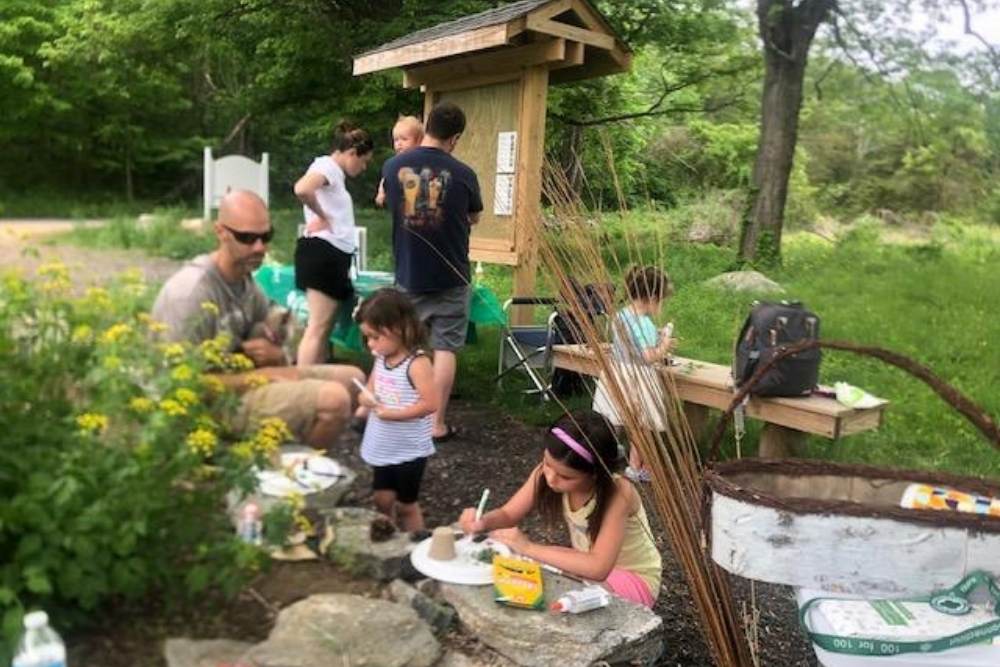 Families doing arts and crafts in front of a trailhead