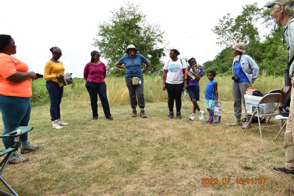 Members of Outdoor Afro stand in a semi circle reflecting on the bird walk.
