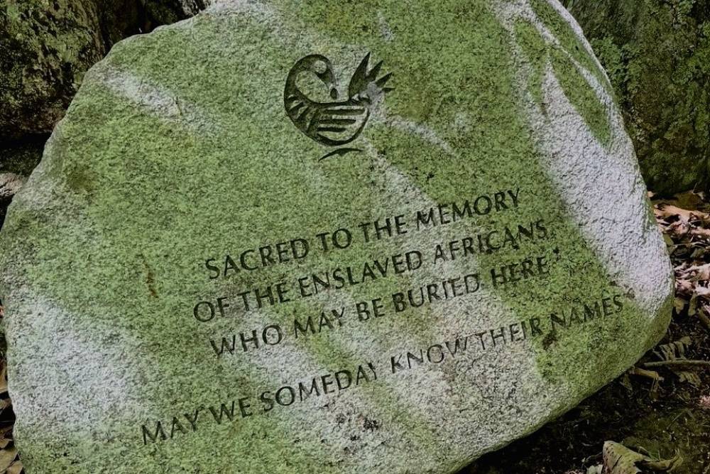 Stone with the words etched "Sacred to the Memory of the Enslaved Africans who may be buried here. May we someday know their names."