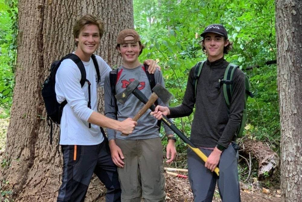 Three young male interns posing outside in the woods