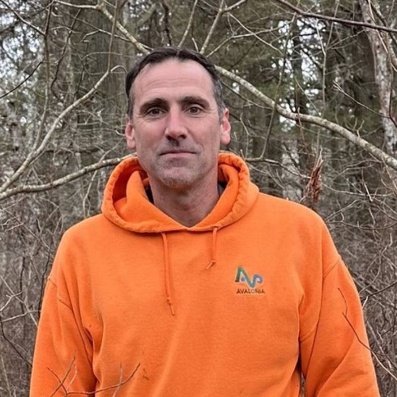 Man out in the woods in an orange hoodie