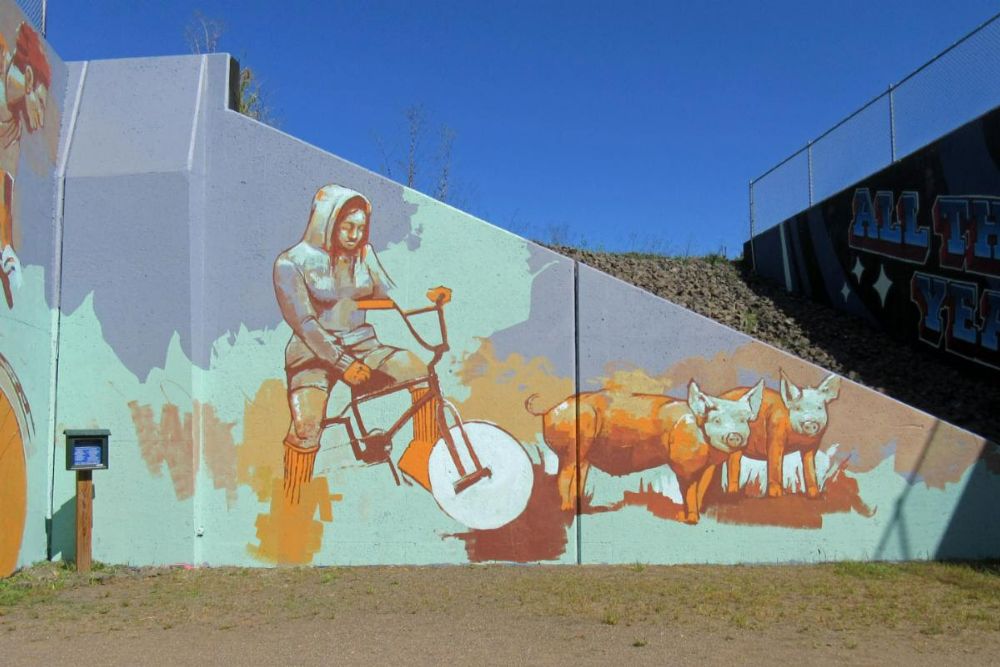 Mural of a person on a bike with two pigs next to them