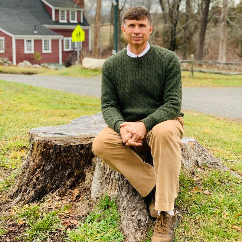 Man outside sitting on a tree stump