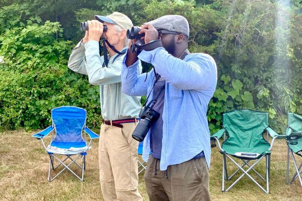 Two men looking through binoculars while birding outside